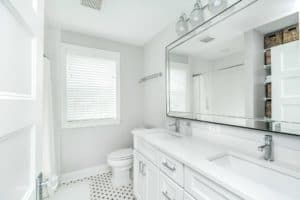 View of bathroom on and large mirror across shared sinks