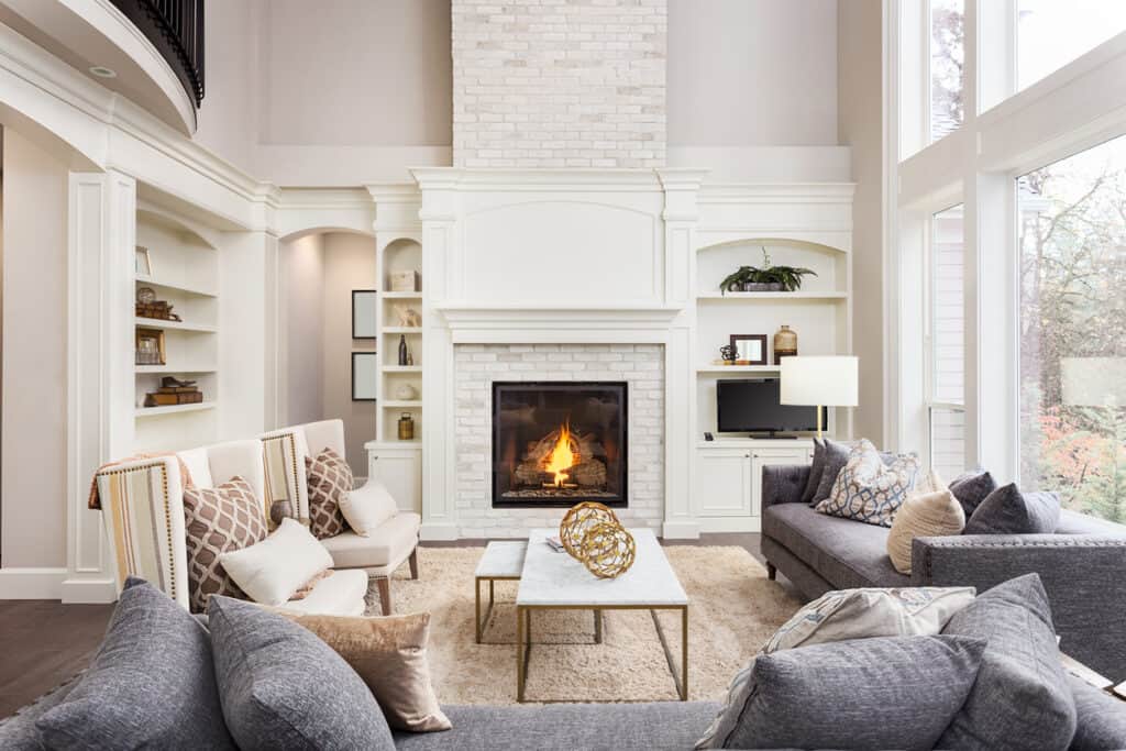Beautiful living room interior with tall vaulted ceiling loft area hardwood floors and fireplace in new luxury home Has large bank of windows
